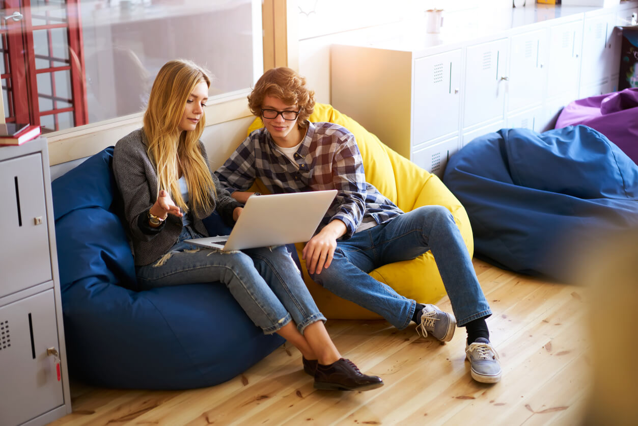 Des étudiants assis sur des poufs confortables, en train de parler et de travailler ensemble. L'image met en valeur la convivialité et le partage entre les locataires d'un logement étudiant Rennes