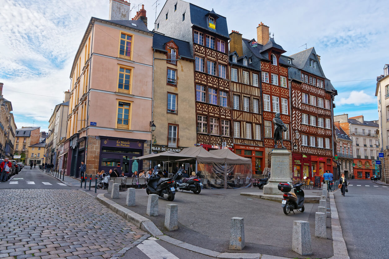 vue sur la ville de Rennes, mettant en valeur la beauté d'un immeuble coloré. La rue abrite des commerces et reflète l'attrait de la ville où la résidence étudiante Rennes est très recherchée